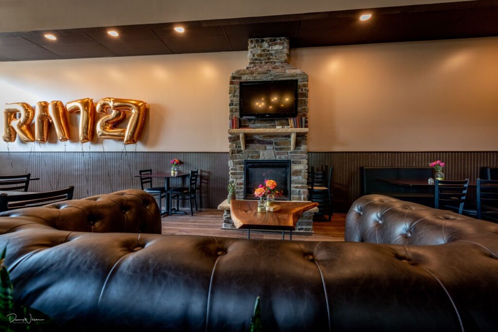 Rm 727 Leather seating facing a fireplace with a TV and Bookshelf placed above