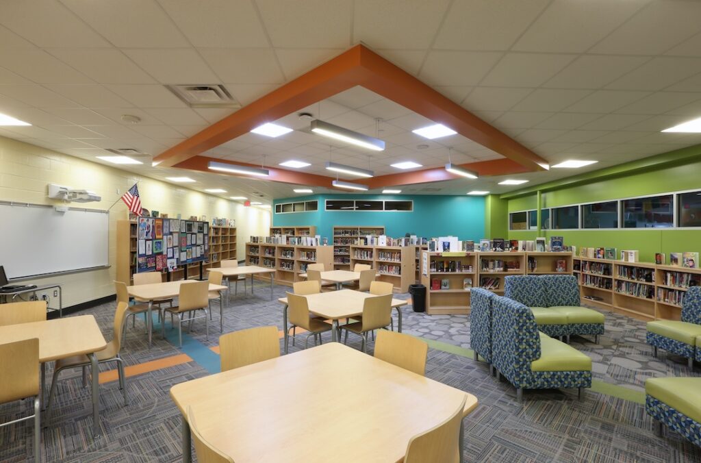 Streetsboro Middle School Media Center filled with group tables, lounge furniture, bookshelves, whiteboard and projector
