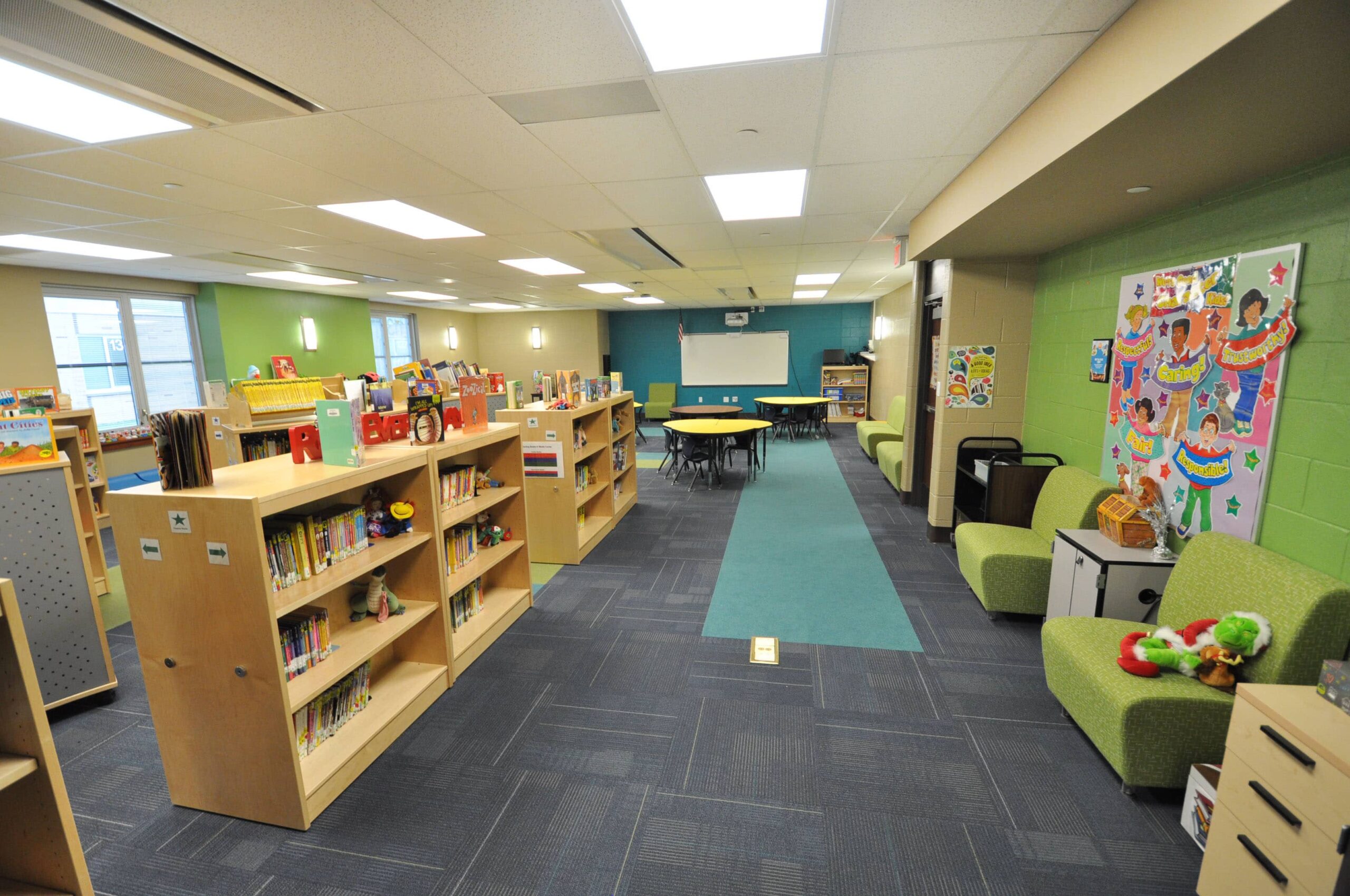 Streetsboro Elementary School Media Room filled with bookshelves, lounge furnitures, screen projector and tables with chairs