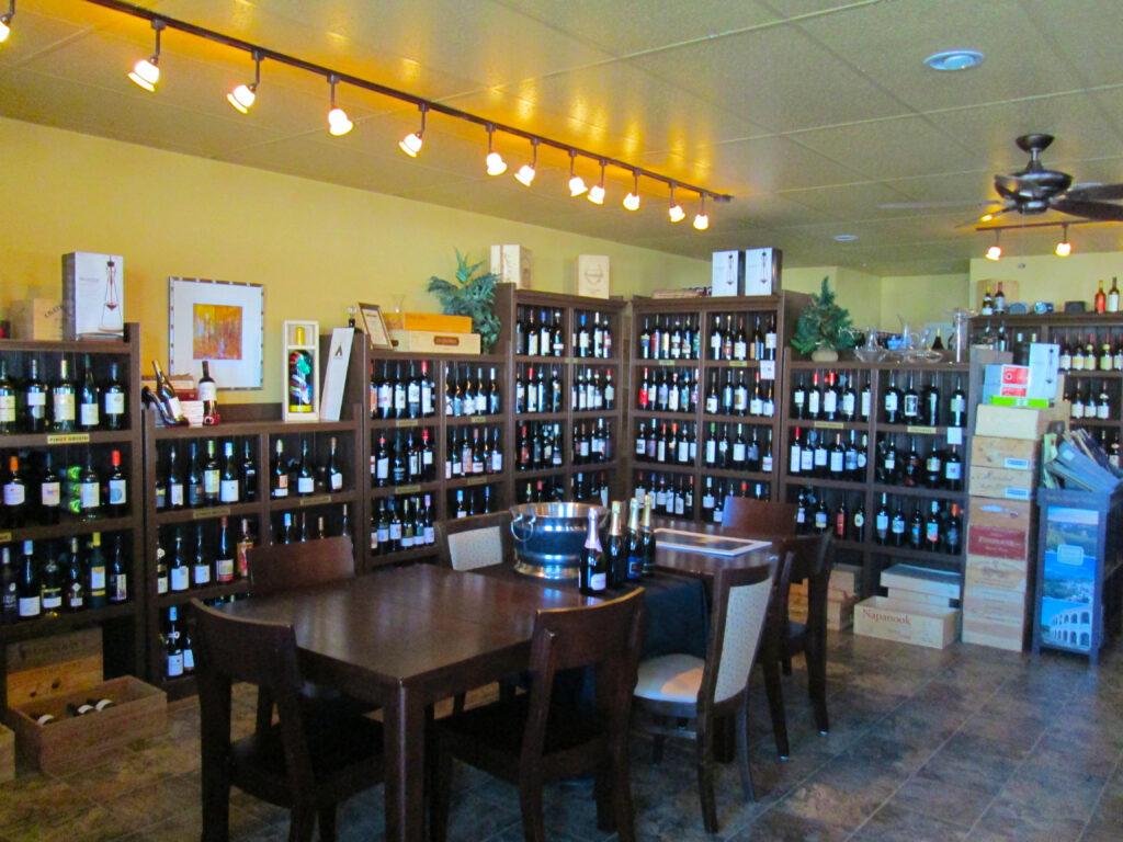 Regency Wine Cellars Interior - Dinning tables in front of a bar top with retail shelves lined with wine bottles in the background